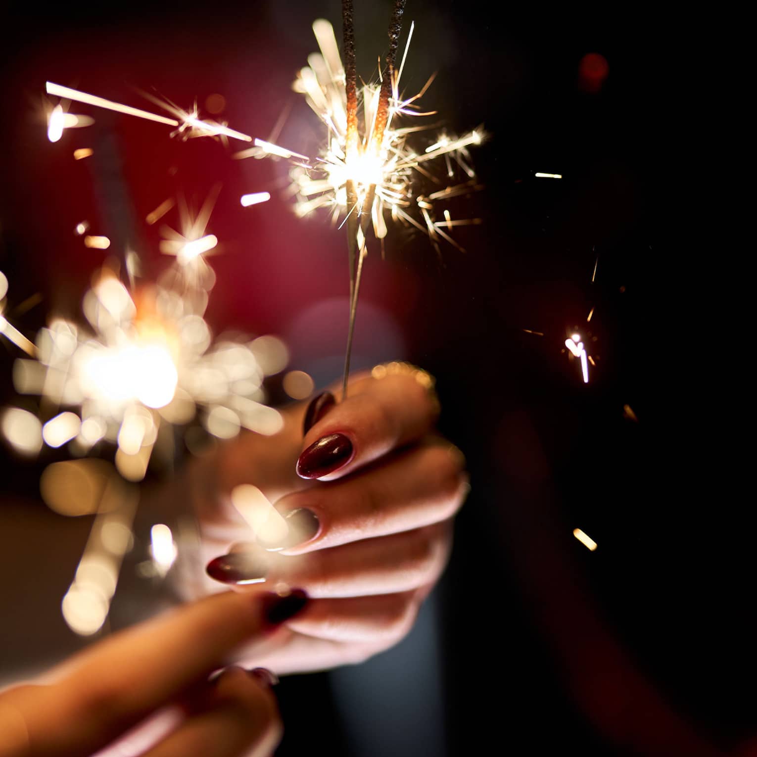 Hands holding a lit sparkler.