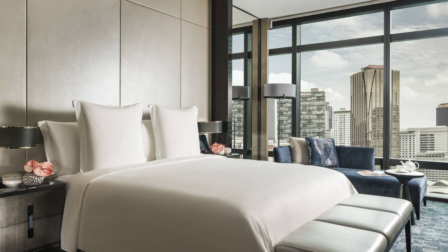 Bed and leather bench in front of padded wall, floor-to-ceiling wall of windows