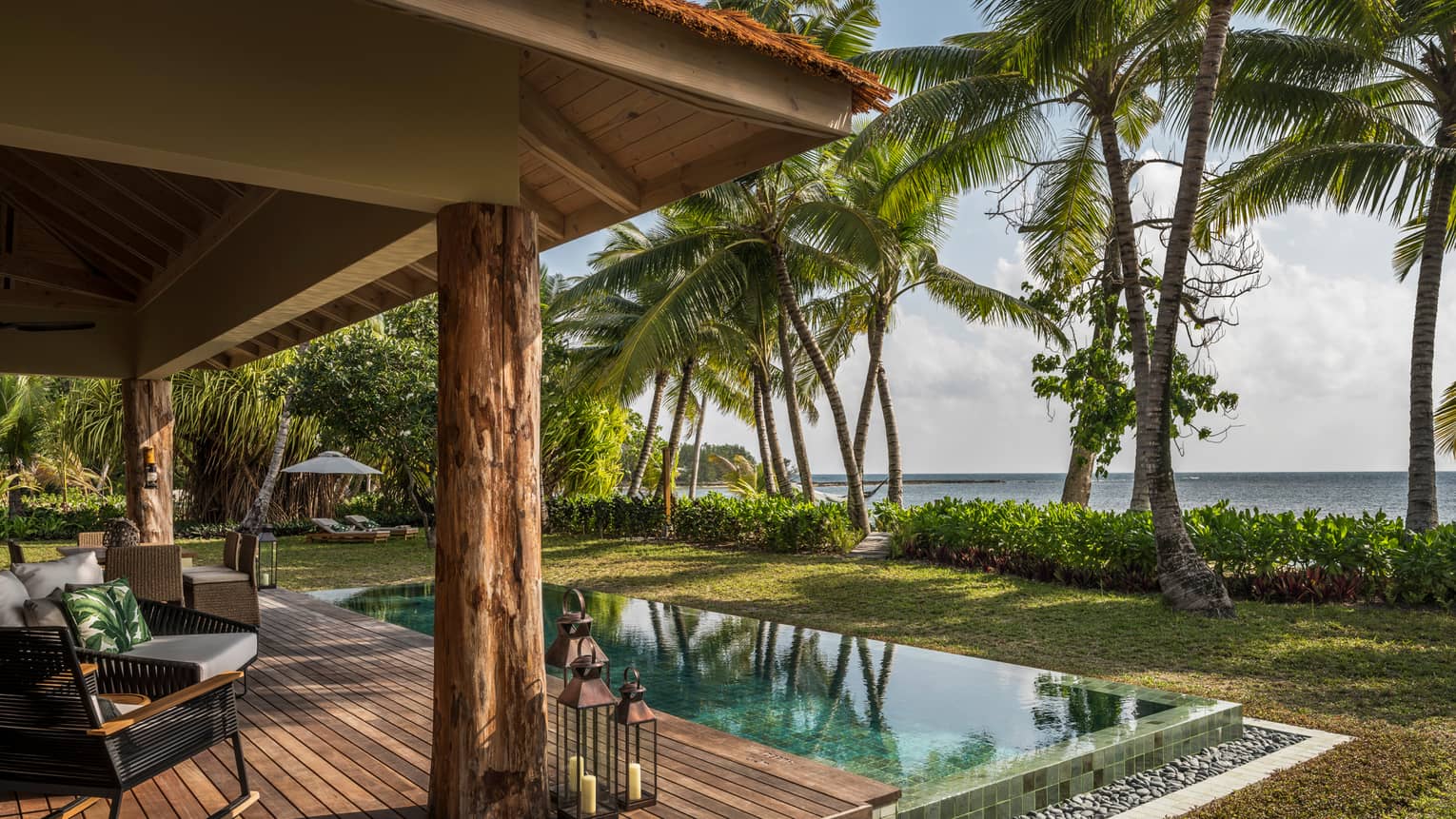 Two-Bedroom Villa wood patio with roof, infinity swimming pool, palm trees in front of ocean view