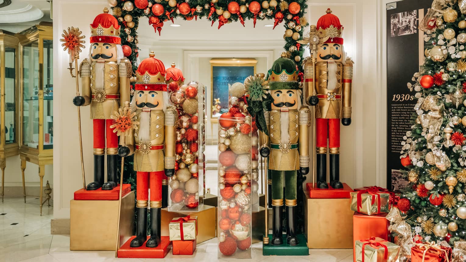 HOtel lobby holiday display featuring four life-size nutcrackers; red, gold and silver ornaments; garlands and a tree surrounded by red and gold presents