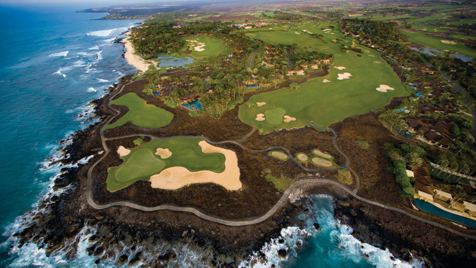 Aerial view of Hualalai Golf Course along rocky shore and ocean