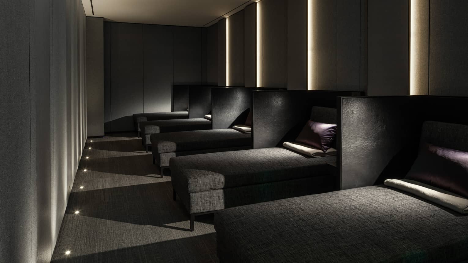 Row of lounge chaises with pillows, blankets in dark Napping Room