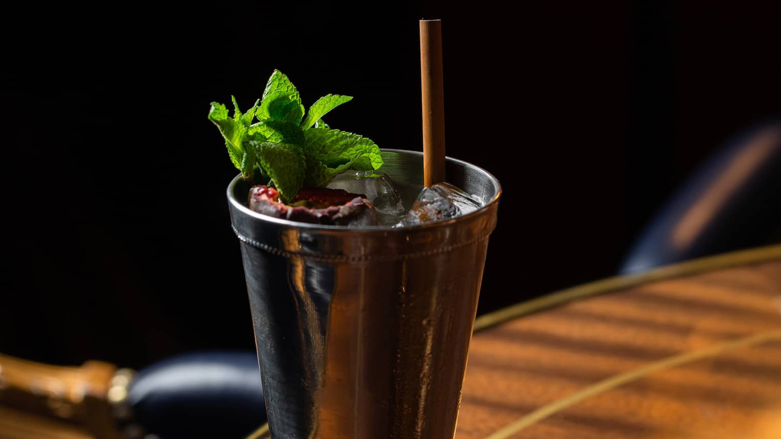 A cocktail with green herbs in a metal glass.