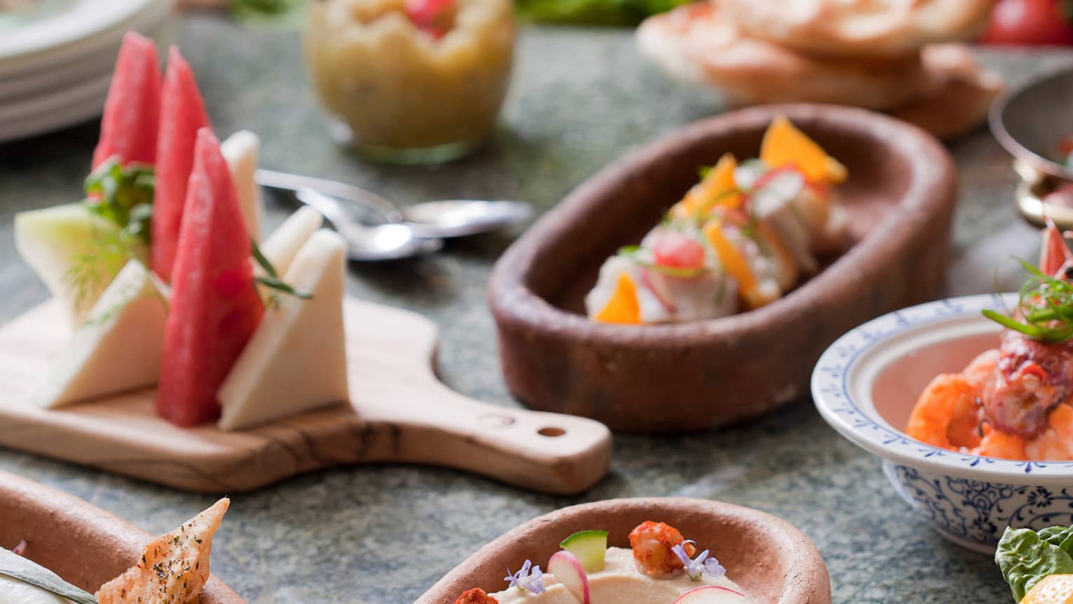 Small clay and wood dishes with appetizers, cheeses, fruits