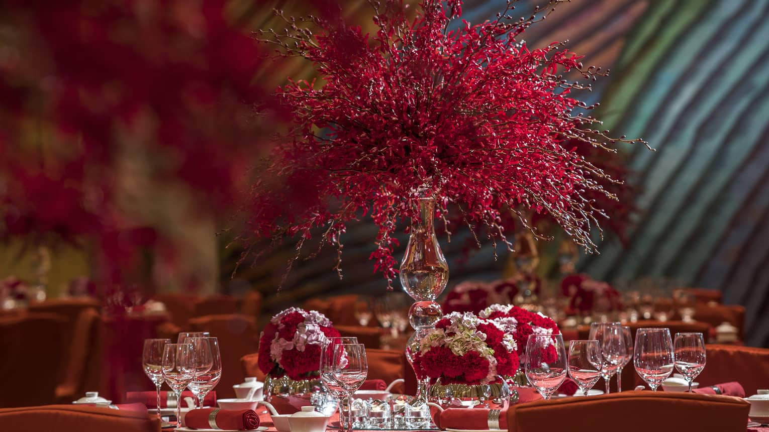 Close-up of banquet dining table with red tablecloth, red and white flower displays