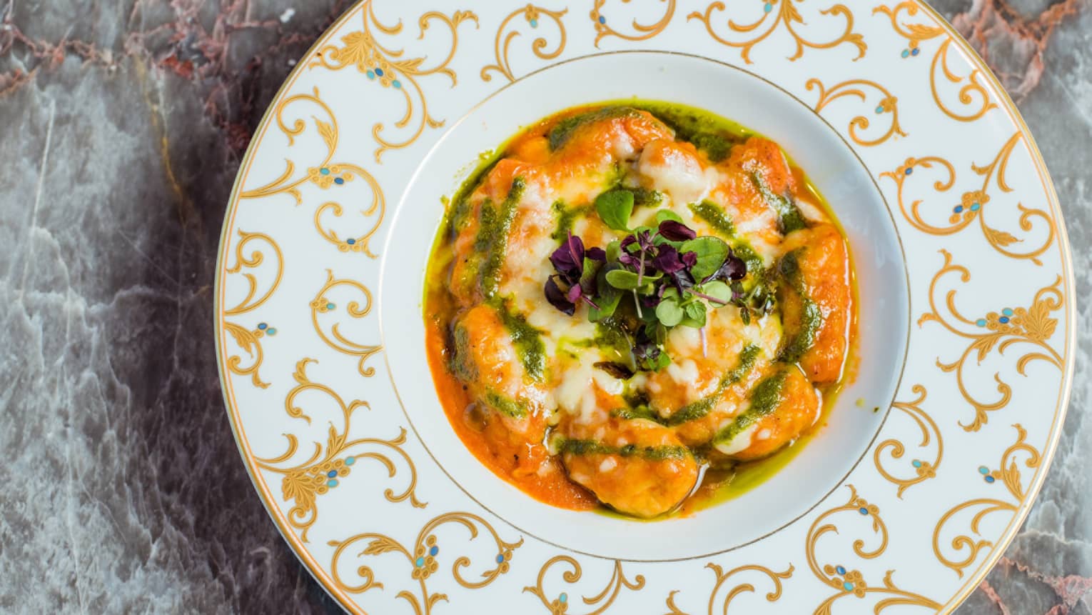 A white plate with golden accents, filled with an orange stew.