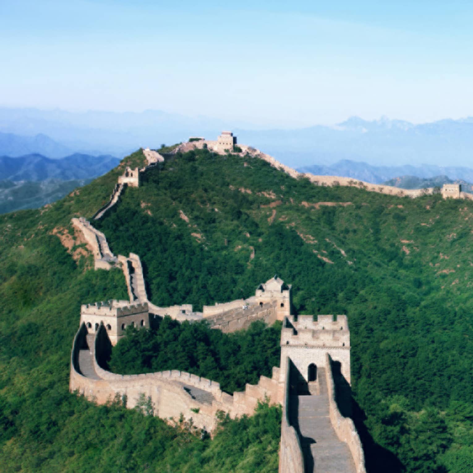 Stone watchtowers connected by stone walkways sit on the crestline of a lush, forested mountain range under a blue sky.