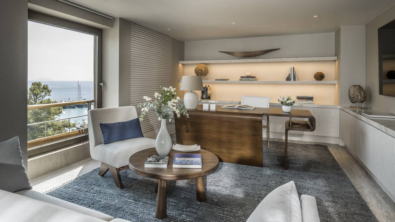 Arion Riviera Suite office with large wooden desk, white accent chair, round coffee table, backlit built-in shelves, ocean views