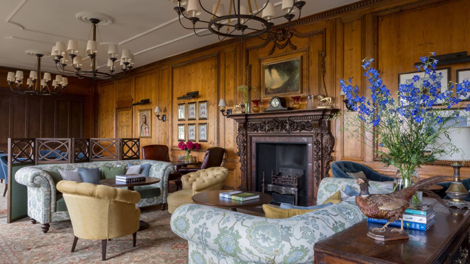 The Library, antique-style blue floral sofas, armchairs, rustic wood walls, soaring ceilings