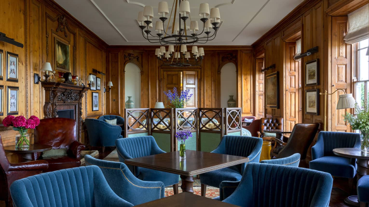 Blue velvet lounge chairs around tables in The Library, wood walls, chandelier