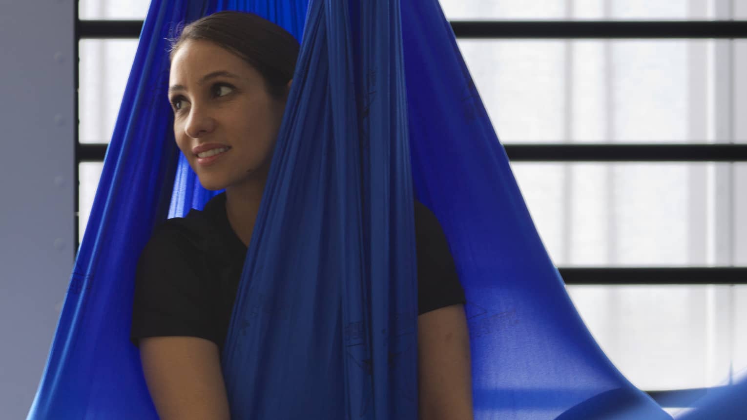 Woman sitting cross-legged in royal blue anti-gravity swing