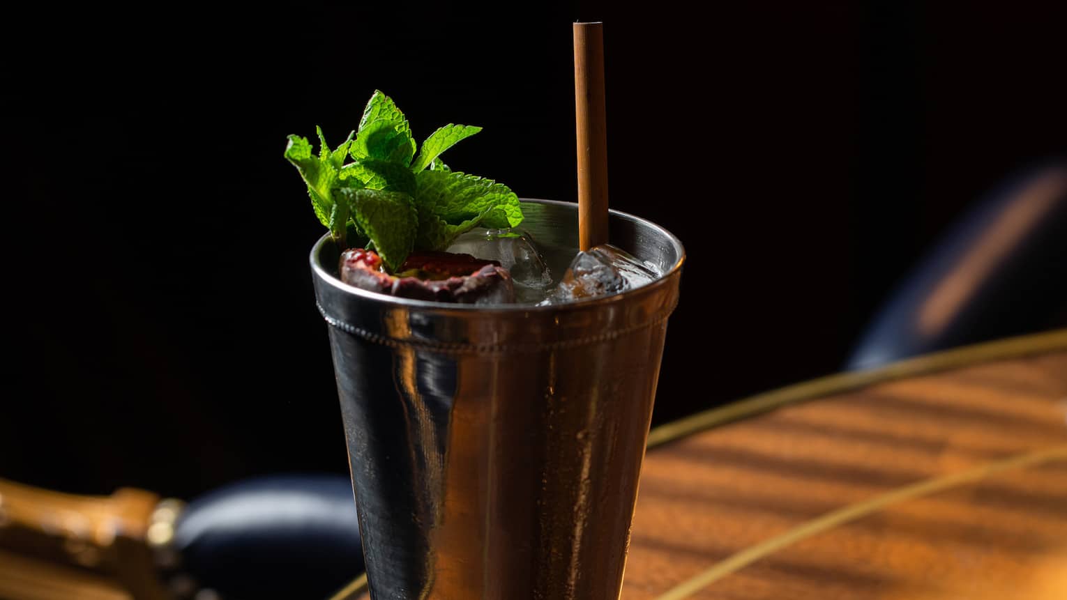 A cocktail with green herbs in a metal glass.