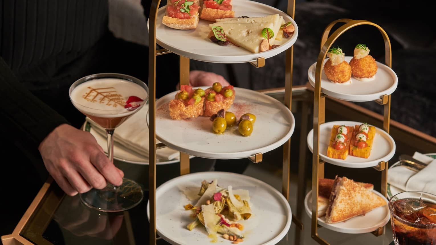 A server setting up tapas on a three-tiered afternoon tea stand