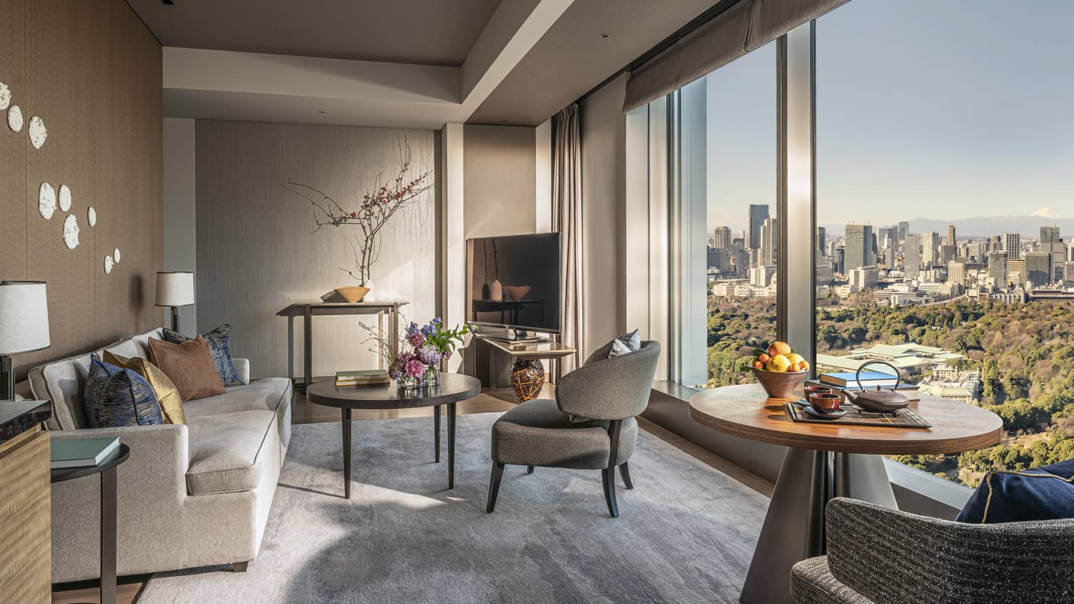 A modern living room and seating area by a large window overlooking the city