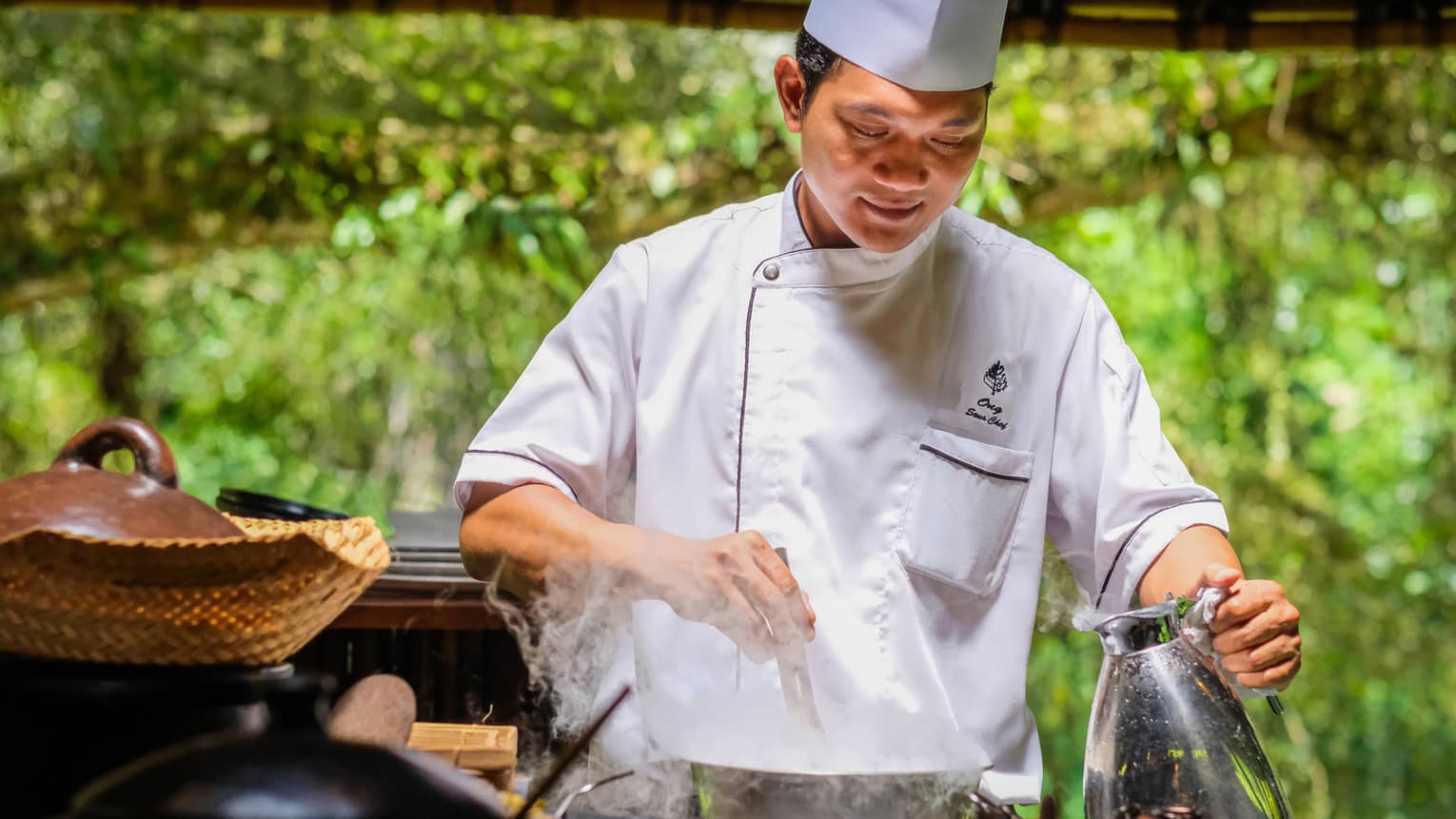 Chef prepares food in traditional woks outdoors