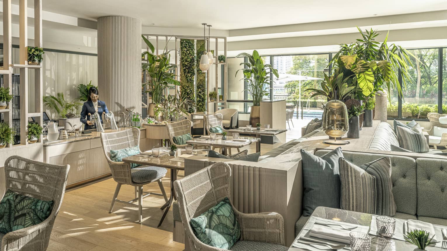 Pool House dining area with natural light, potted palms, rattan chairs and light blue sofas