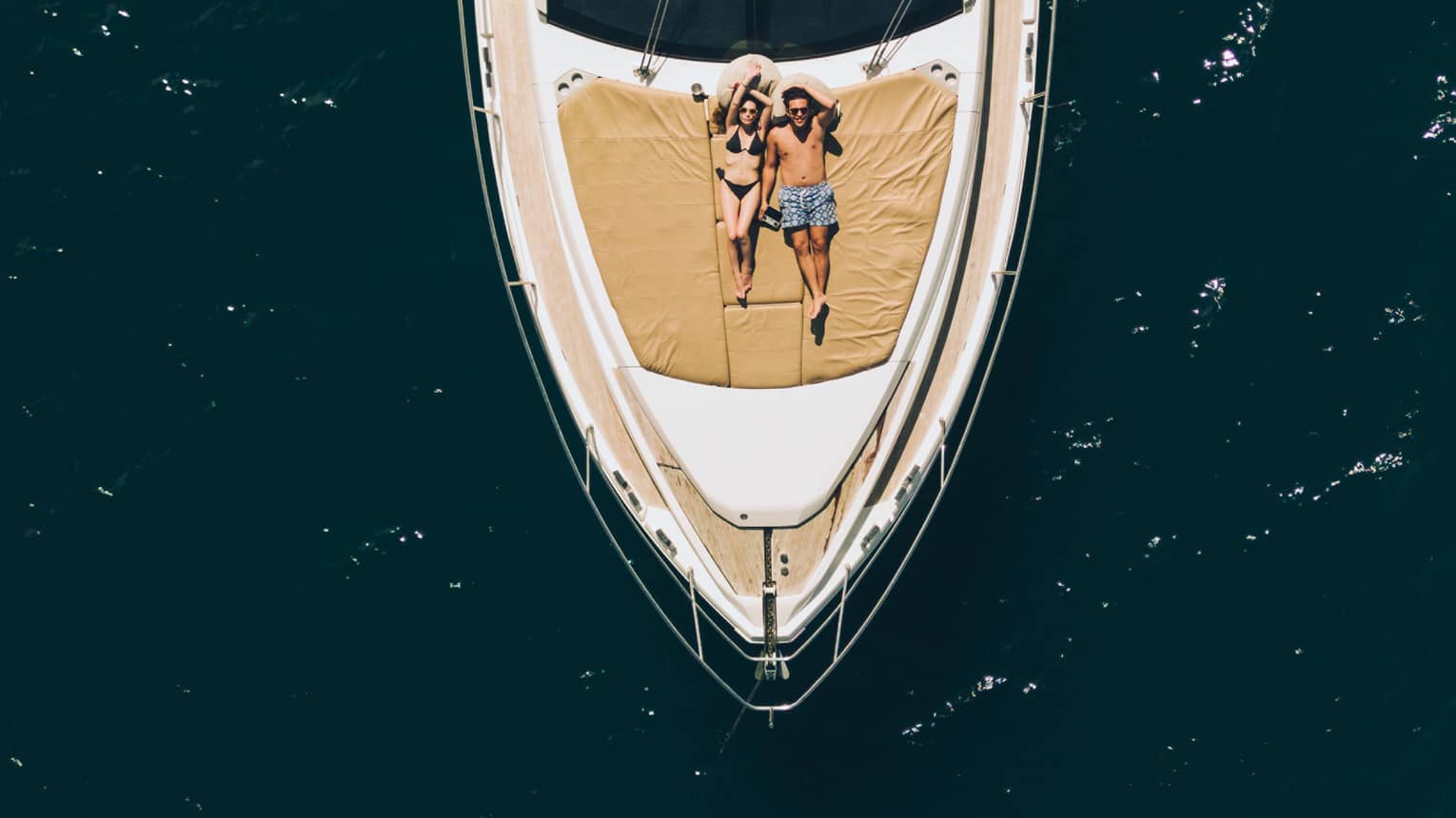 Aerial view of couple relaxing on the front of a large boat