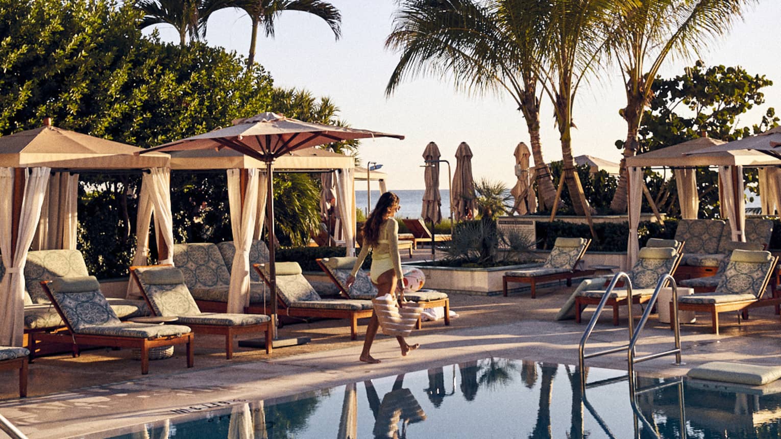 Guest walks by a row of poolside cabanas