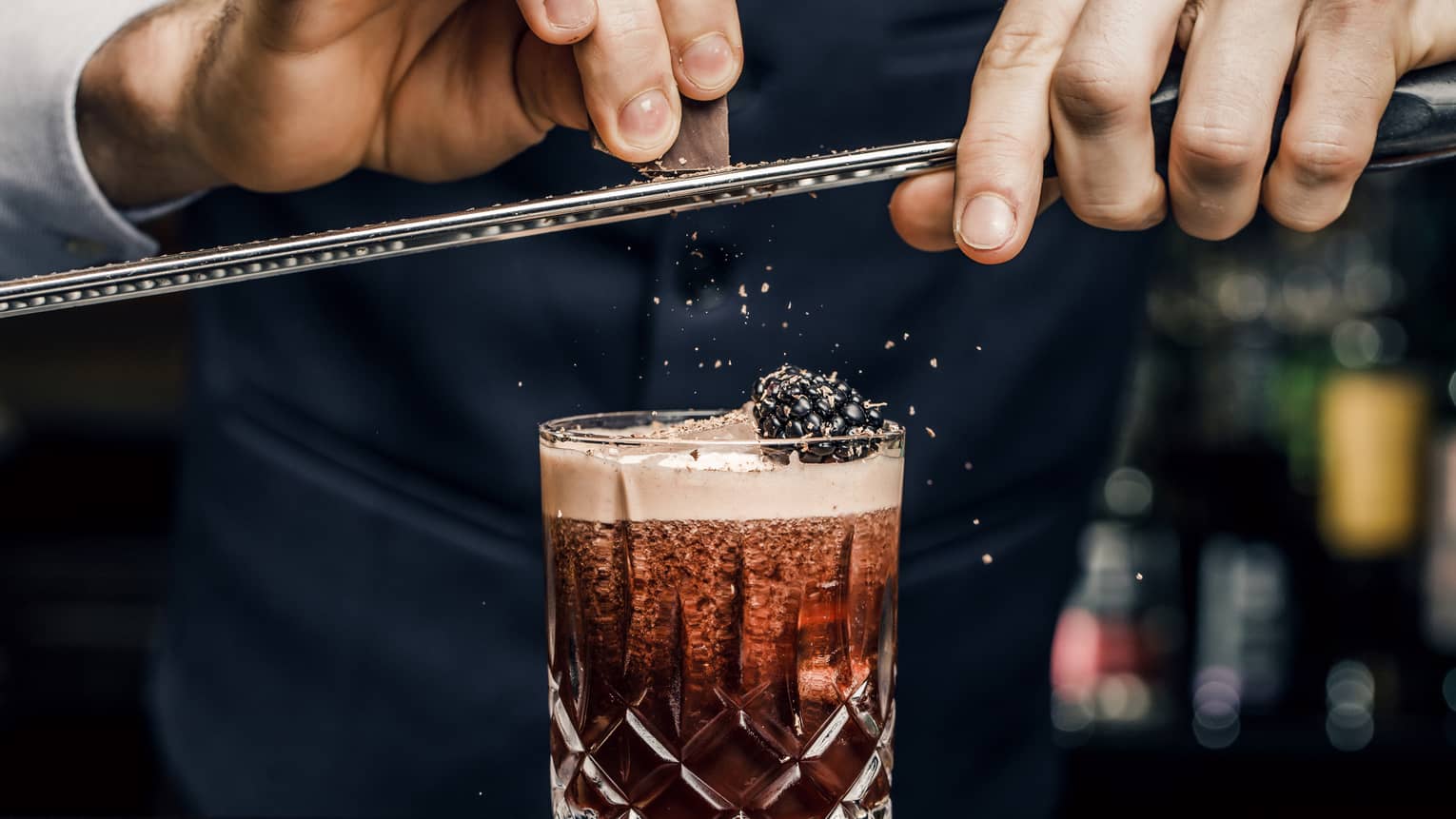 Churchill Club bartender shaves garnish over cocktail in crystal rock glass with blackberry