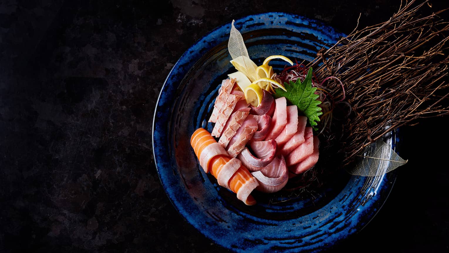 Slices of raw fish sashimi, seaweed, pickled ginger arranged on plate