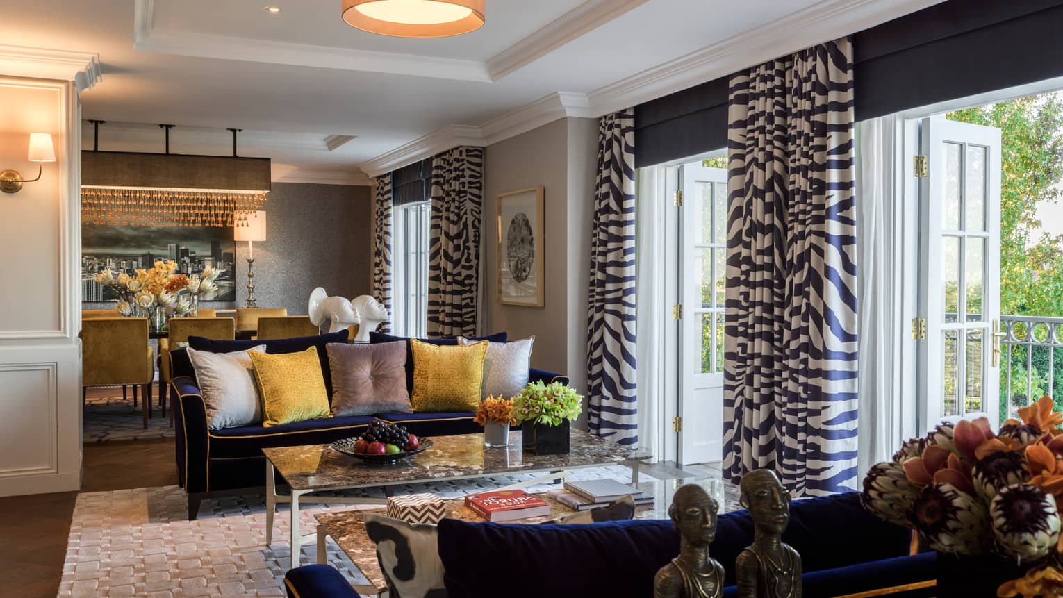 Royal Suite sitting area, two blue sofas with yellow, grey pillows, open patio doors with Zebra print curtains