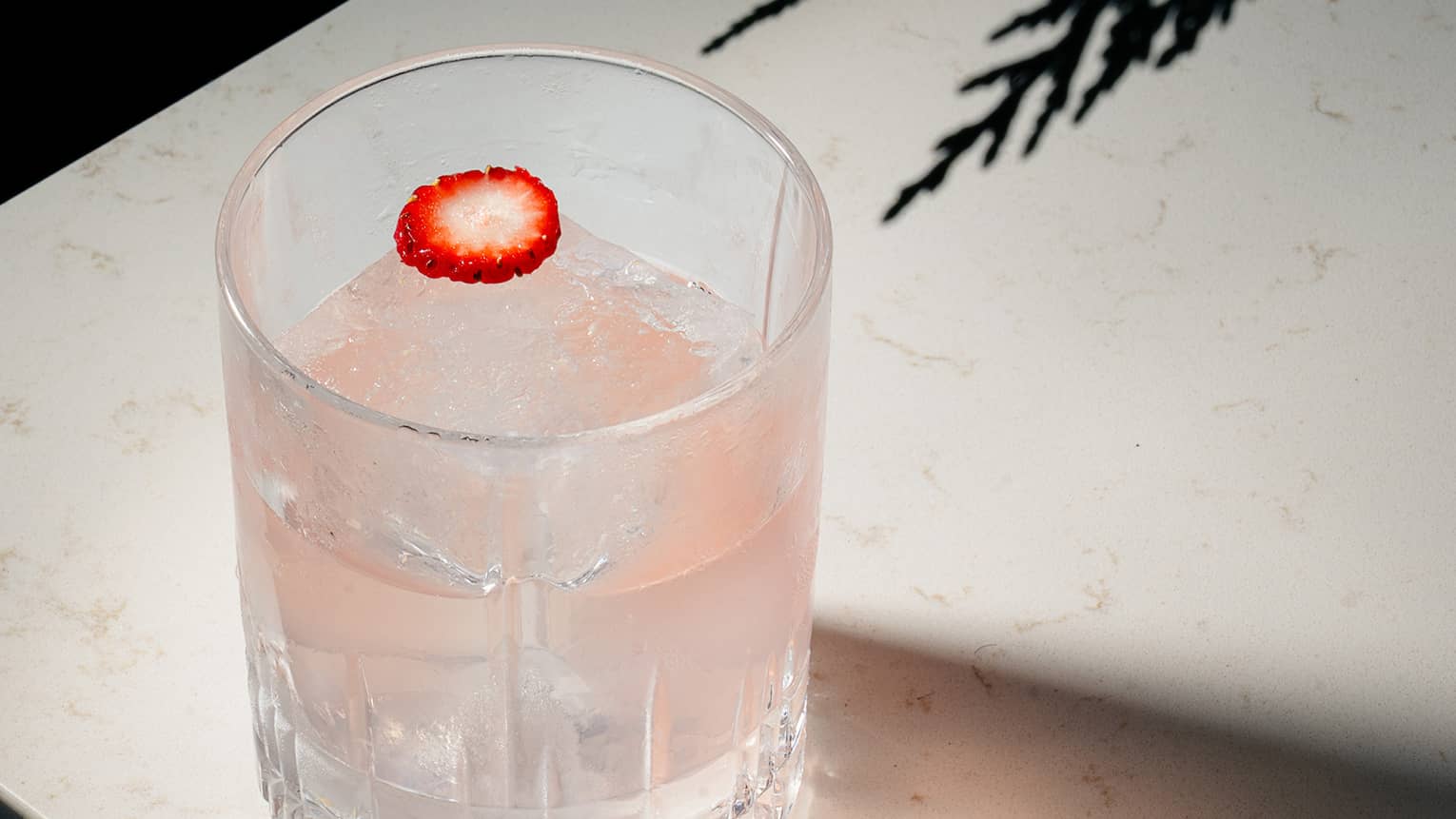 Vodka, strawberry, yogurt, Cocchi Rosa and peach cocktail served in a rocks glass and garnished with a sliver of strawberry
