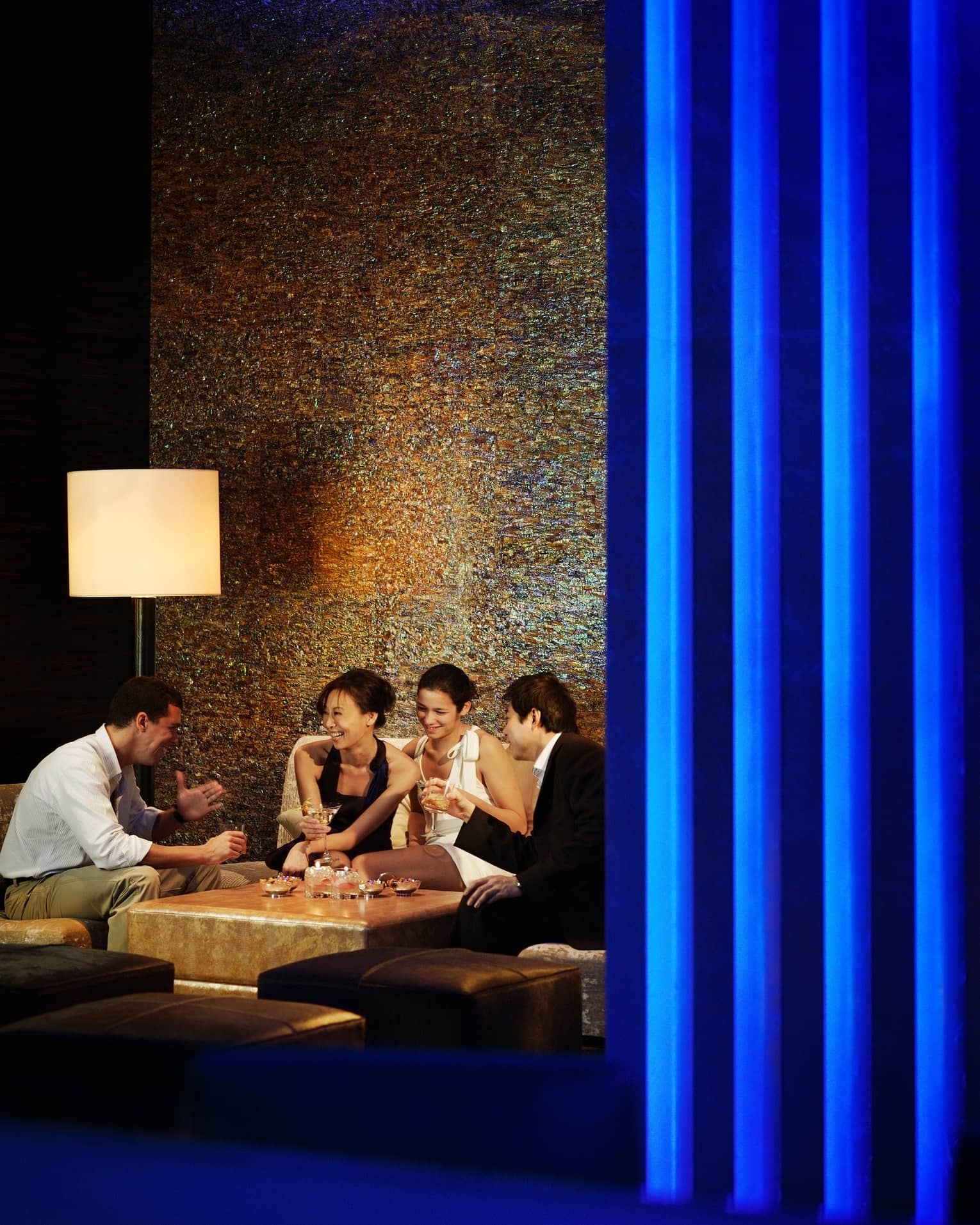 Group of friends laugh, drink cocktails and martinis around Bar Azul lounge table