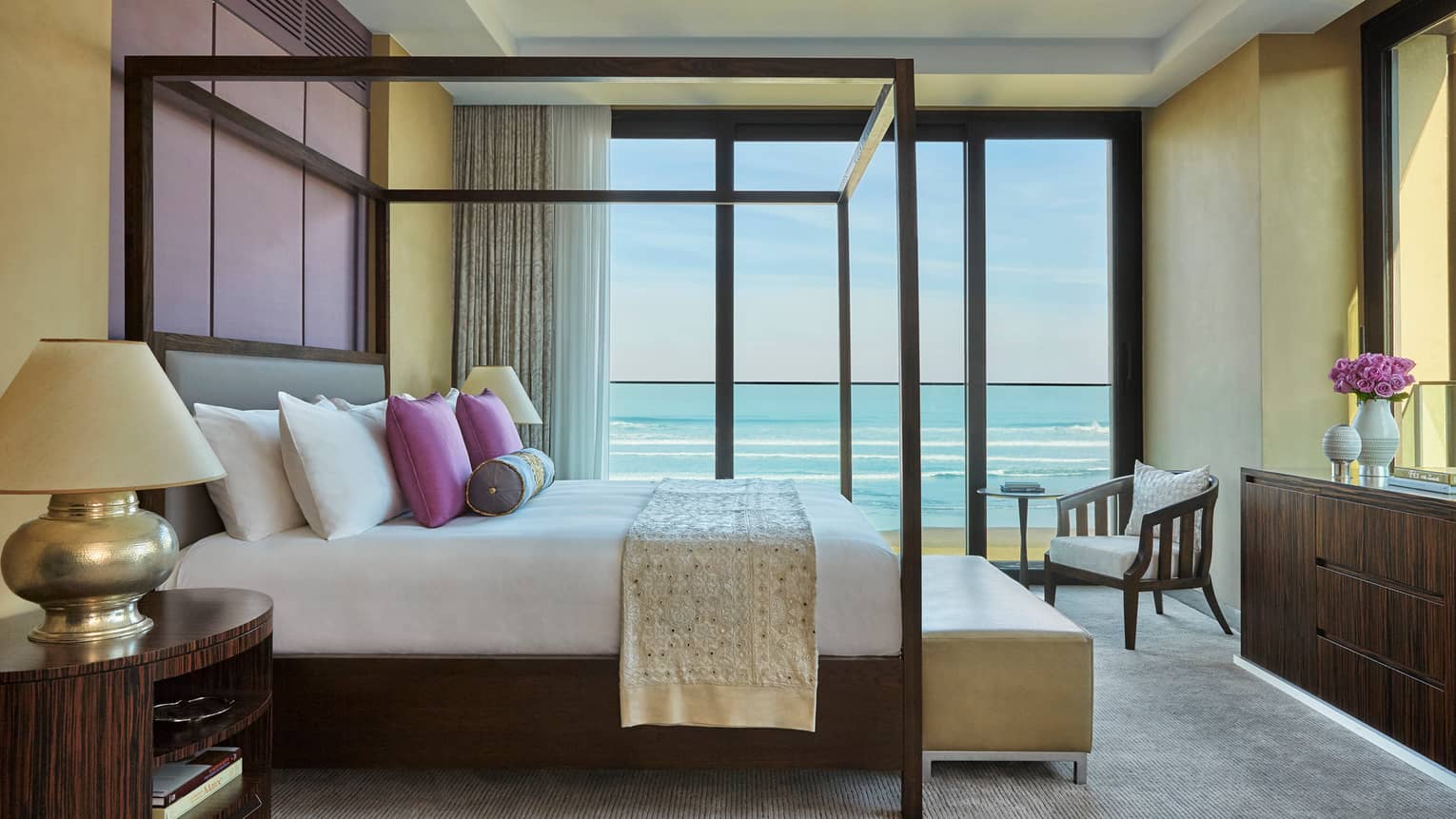 Royal Suite Ocean View poster bed with pillows, white textile, large balcony window with ocean view