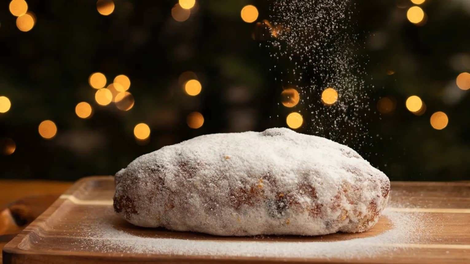 Freshly baked loaf of bread being dusted in white powder with Christmas trees in the background