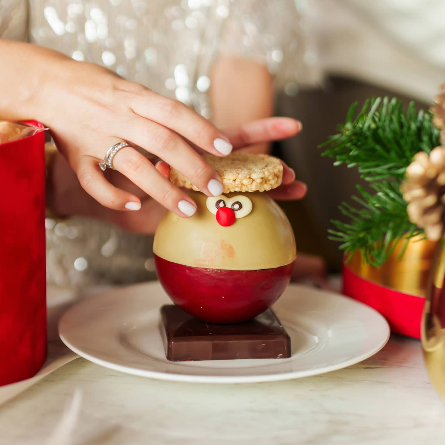 Person placing cooking on top of a holiday-themed round dessert