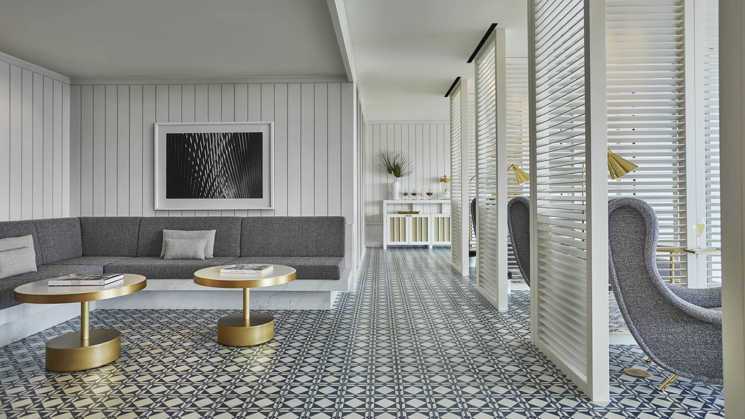 Luxury spa lounge with a gray sectional sofa, gold accent tables, patterned tile flooring and partitioned seating areas with armchairs