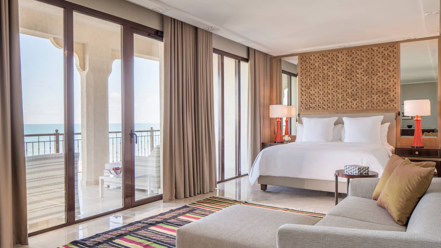 Premier Room bed, L-shaped sofa by floor-to-ceiling windows, balcony doors
