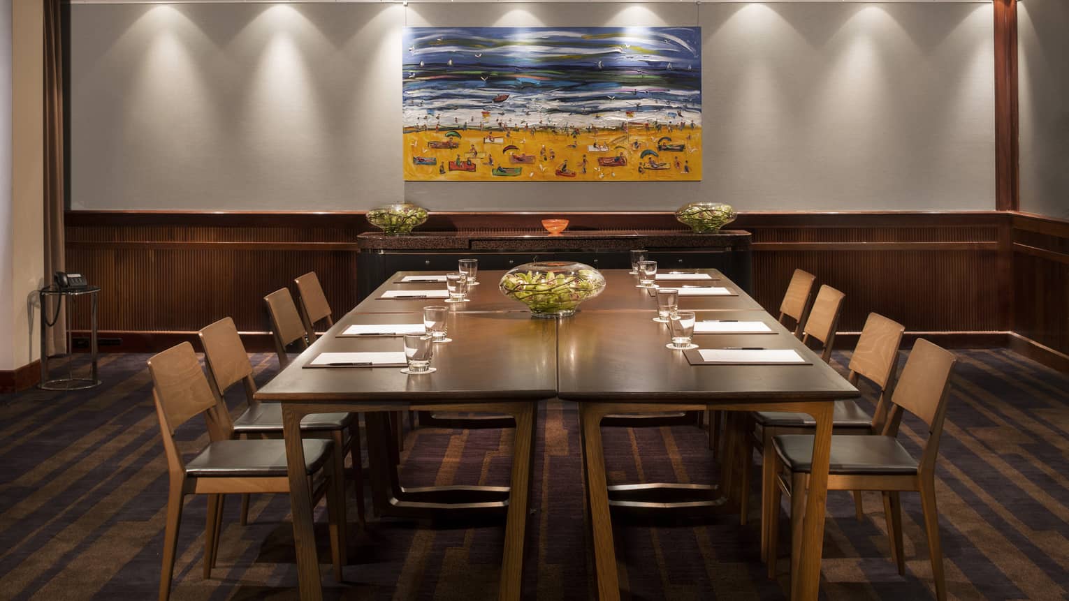 Gallery meeting room with large boardroom table, retro-style chairs under colourful painting of beach