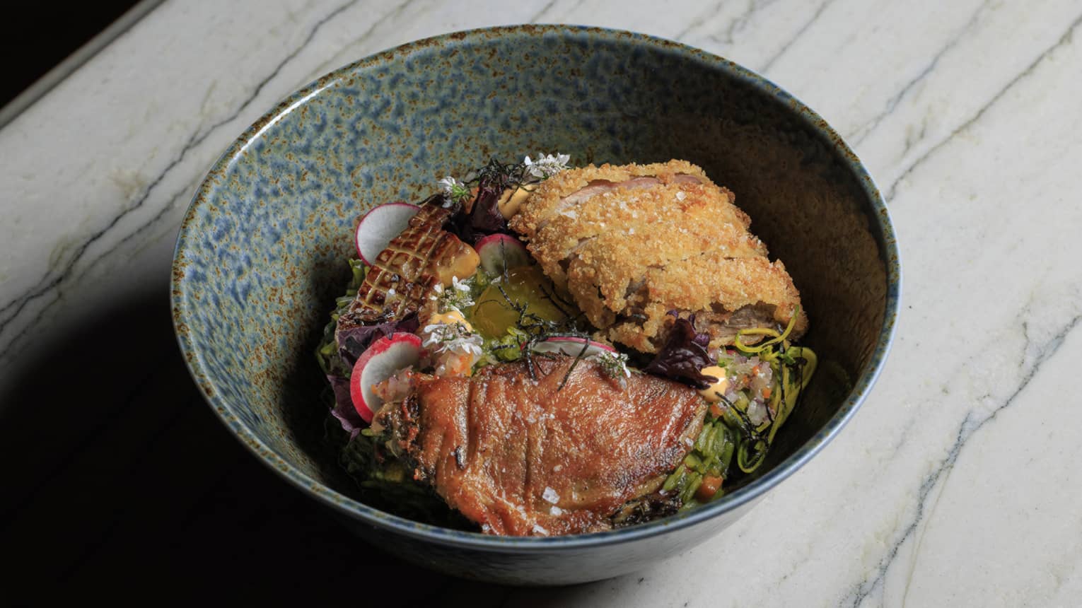 Arroz Con Pato made with cilantro rice, yuzu, confit, kamo katsu, foie gras, shoyu egg yolk and carrots, served in a stoneware bowl