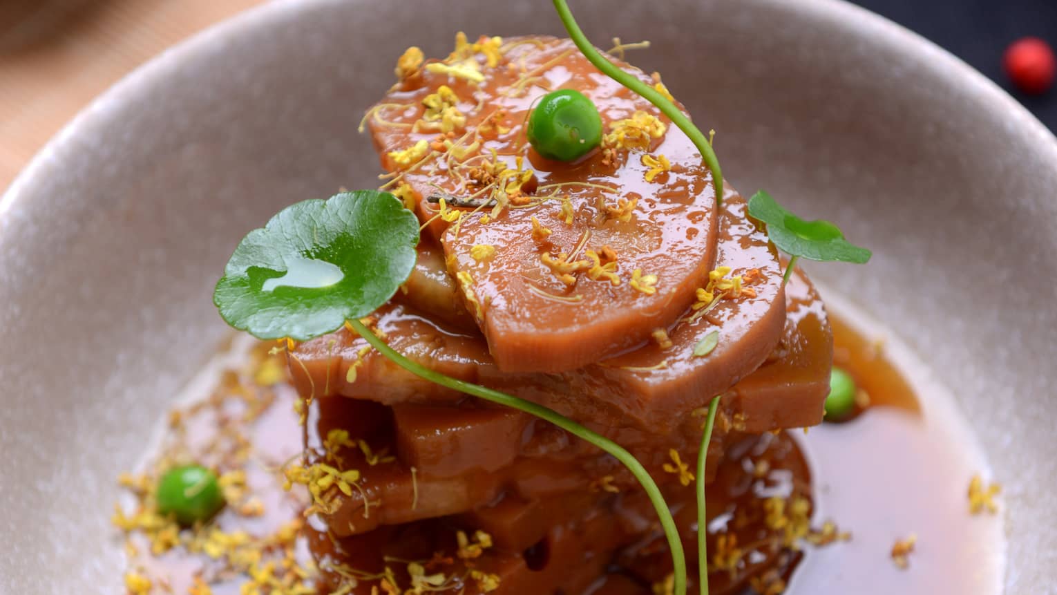 Steamed lotus root stacked on plate with sauce, herbs