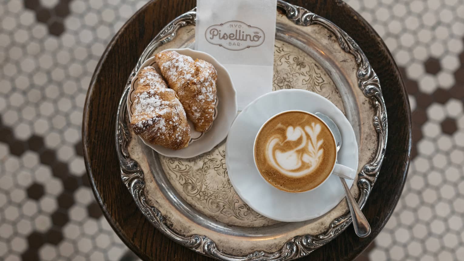 A small table with coffee and pastry on it.