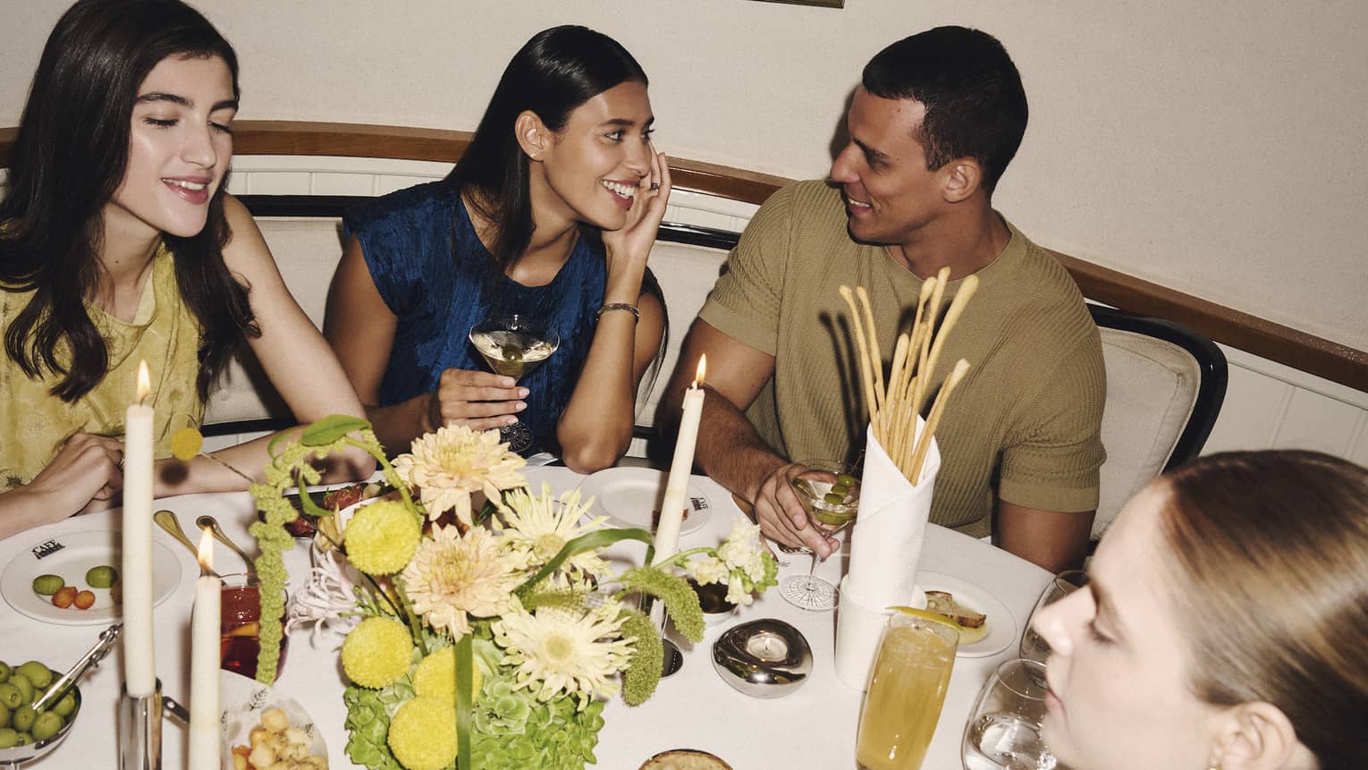 A group of people gather around a restaurant dining table