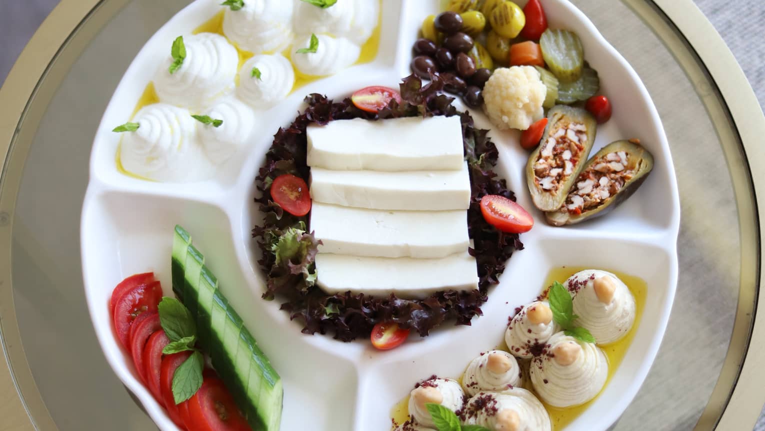Variety of small bites presented in white compartmentalized dish on round table
