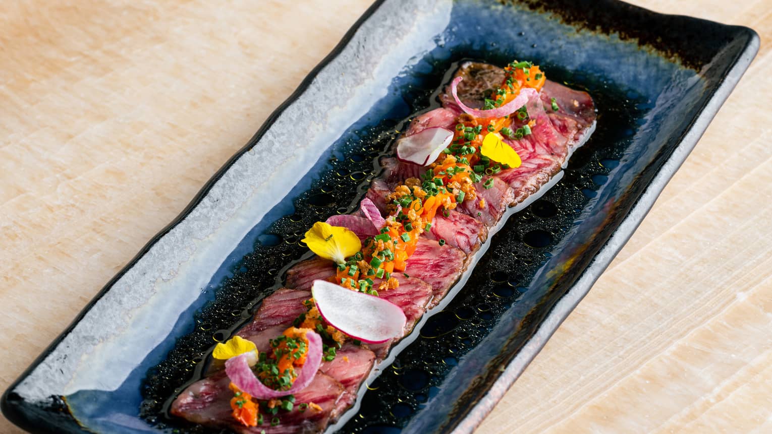 Wagyu Tataki with Yuzu Truffle Ponzu Sauce in rectangular black dish