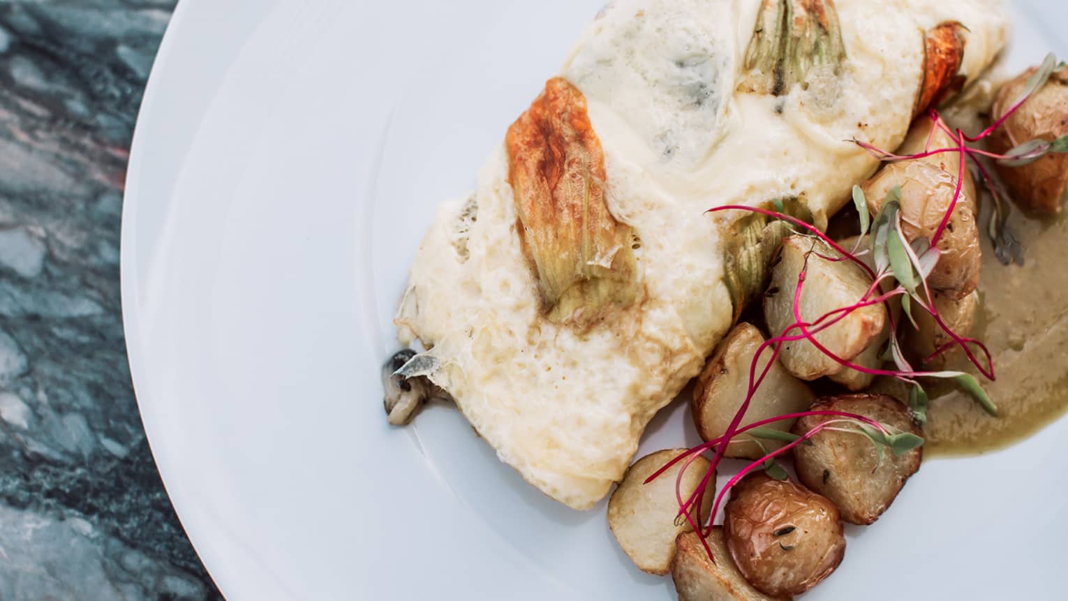 Omelette, made with squash blossoms, Oaxaca cheese, salsa verde and huitlacoche on a white plate.