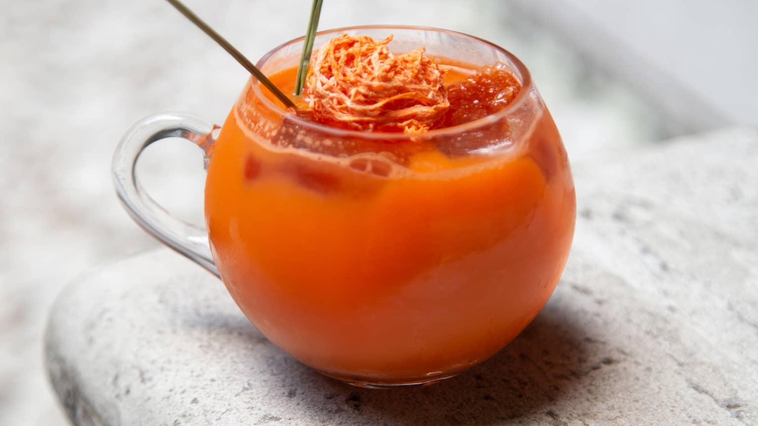 A bright orange drink in a round glass.