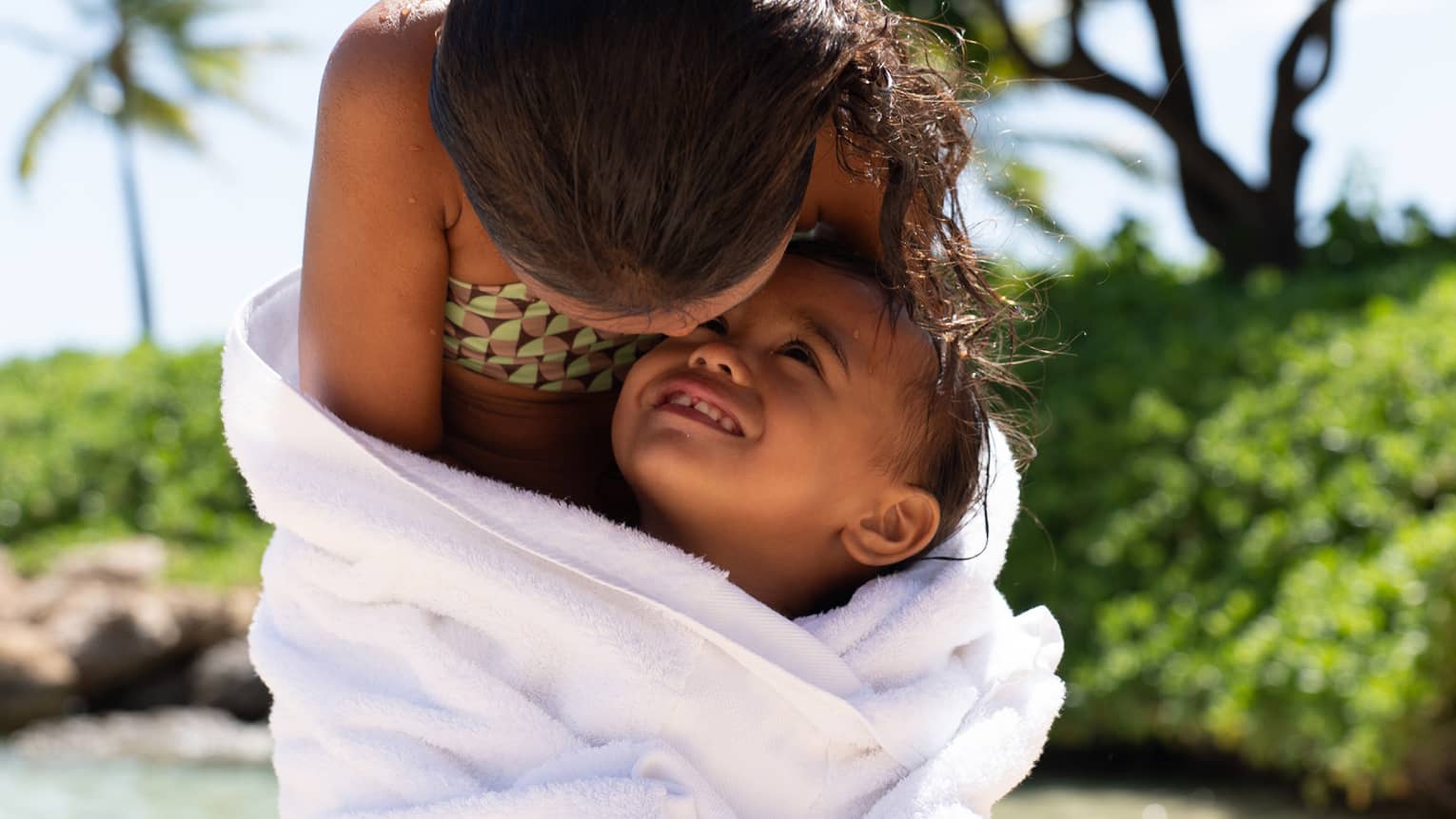 Two young children share towel at tropical beach