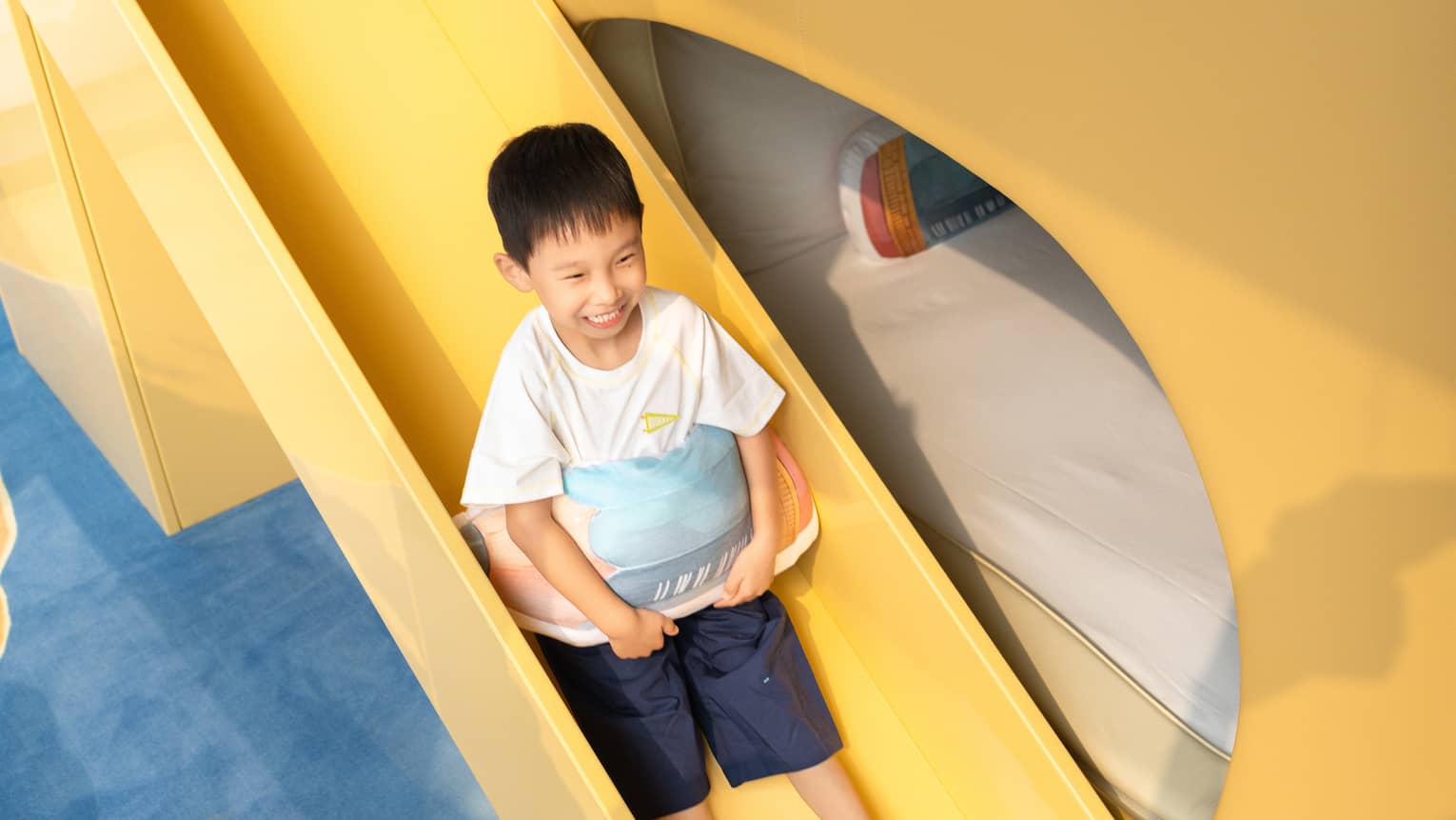 Boy slides down a slide attached to a bunk bed in family hotel suite