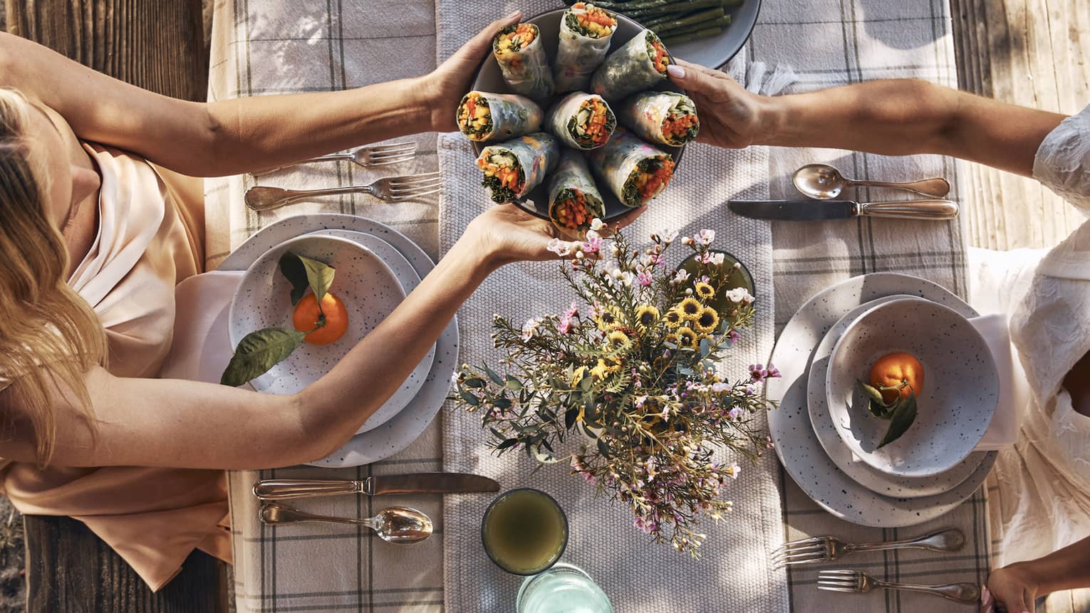 Guests sitting around a table and passing bowls of food.