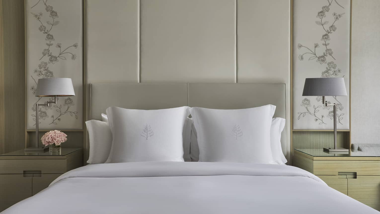 King bed with floral headboard, white sheets and shams, bedside tables