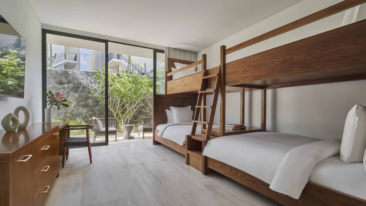 Bedroom with two wooden bunk beds connected together by ladder, walk-out patio