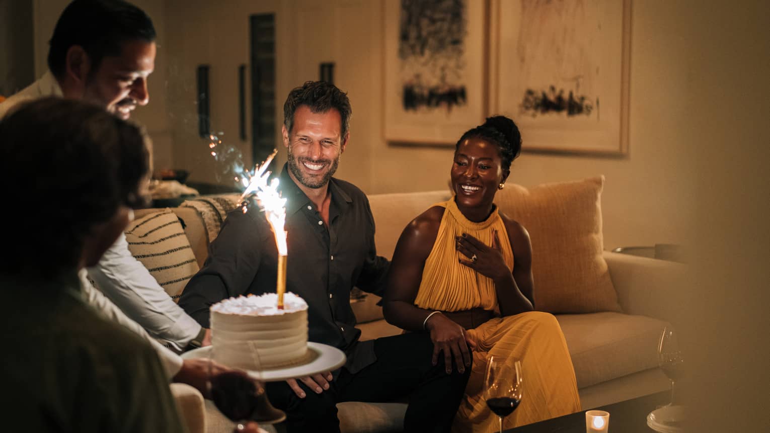 Staff member presenting guests with a lit birthday cake in a residence living room