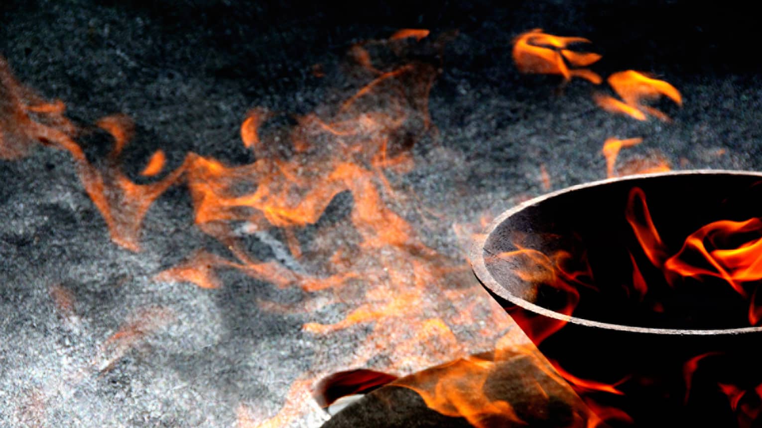 Close-up view of orange-red flames appearing to float in and around a stone bowl set against a variegated dark background.
