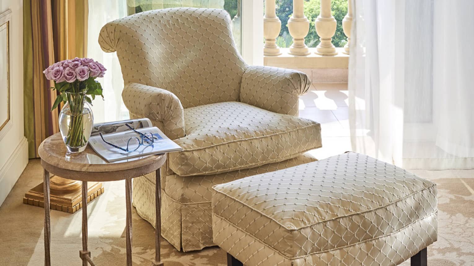 Beige and off white French-style chair with ottoman near window overlooking botanical gardens