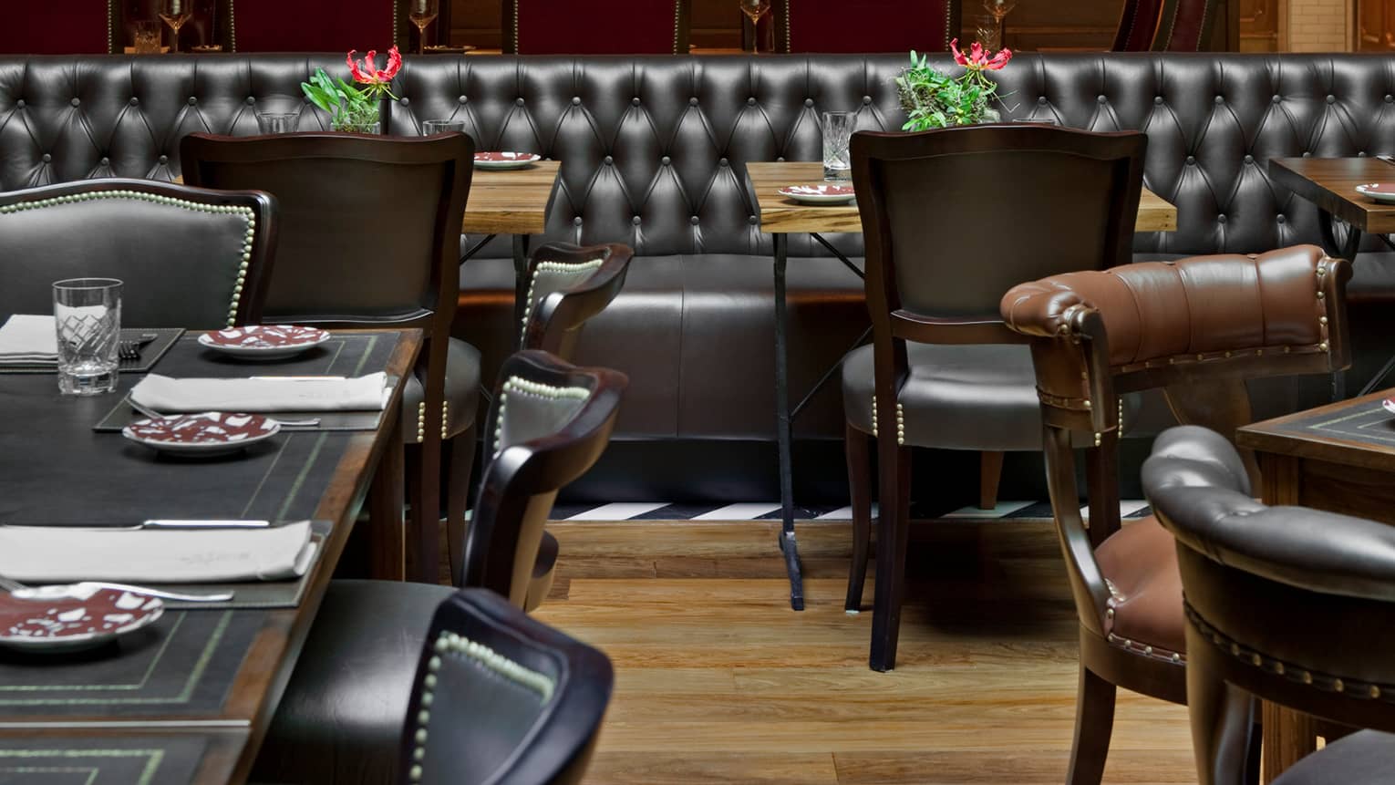Elena dining room long black banquette and dining chairs, cooks on line in background with pans, flames